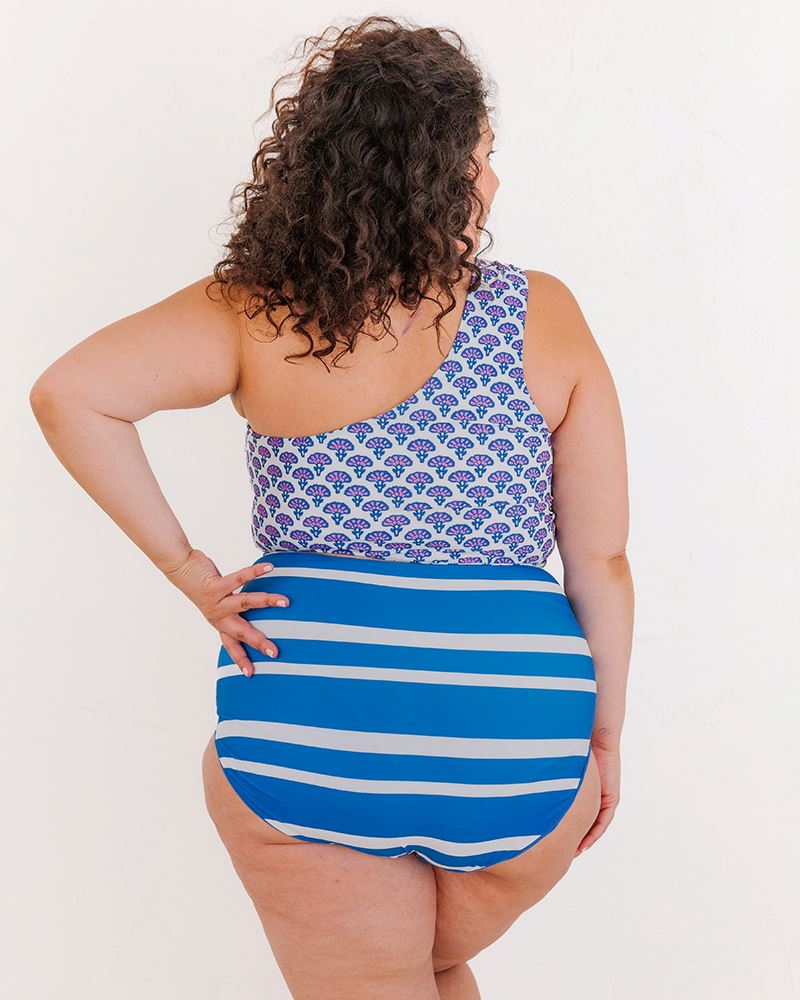 Photo of a woman wearing a Block Floral One-shoulder swim crop top and a blue and white stripe swim bottom back angle