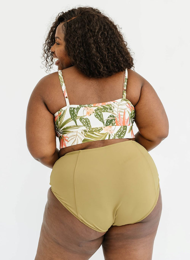 Photo of a woman with her back facing us wearing a green floral cropped swim top with green high waist swim bottoms