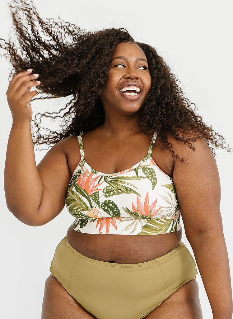 Photo of a woman wearing a tropical floral swim bralette and green swim bottoms