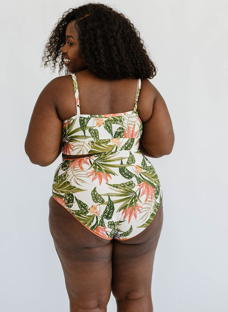 Photo of woman with her back facing us wearing a green floral cropped swim top with green floral high waist swim bottoms