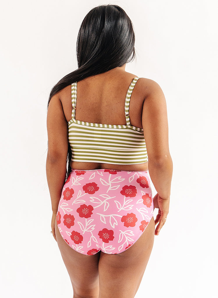 Photo of woman wearing green and white stripe bralette swim top with pink floral swim bottoms back angle