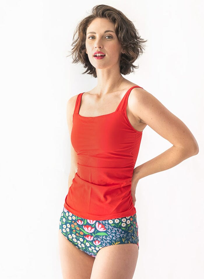 of a woman wearing a Blixen/Indigo reversible swim bottom floral side and a red swim top side angle