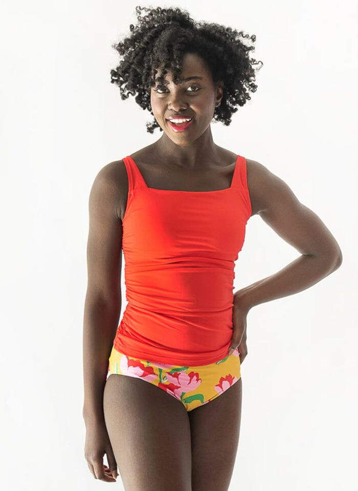 Photo of a woman wearing a Claus/Tage reversible swim bottom Claus side and a red square-neck swim top