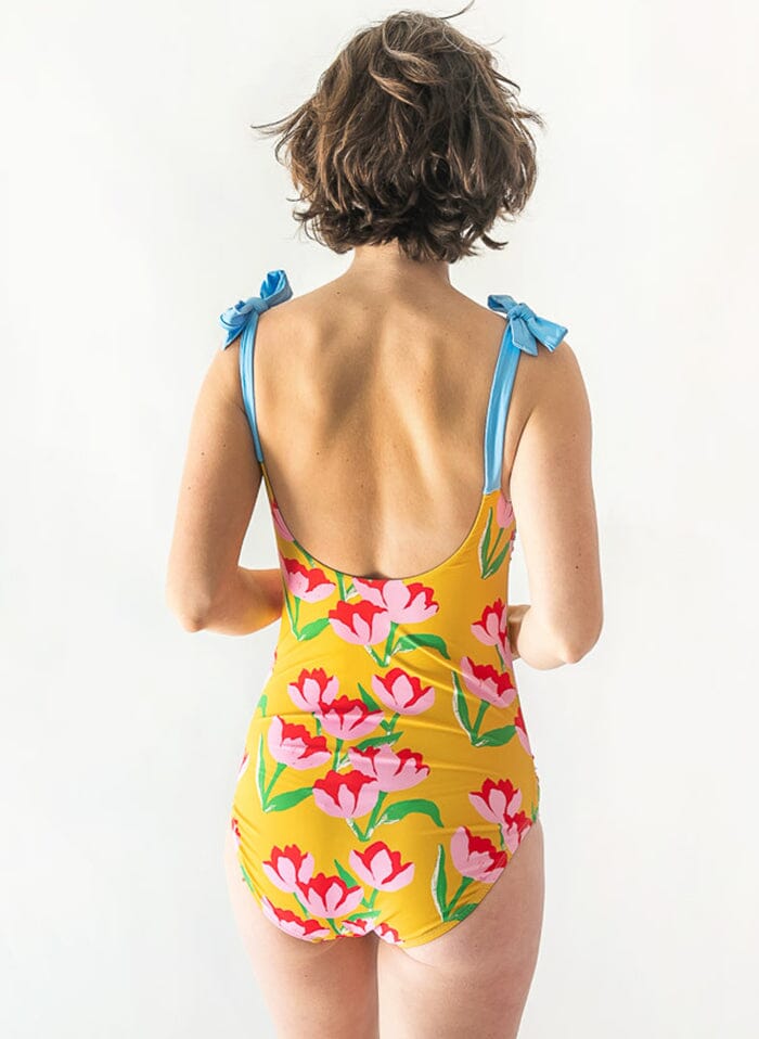 Photo of a woman wearing a Claus shoulder-tie one-piece swim suit back angle