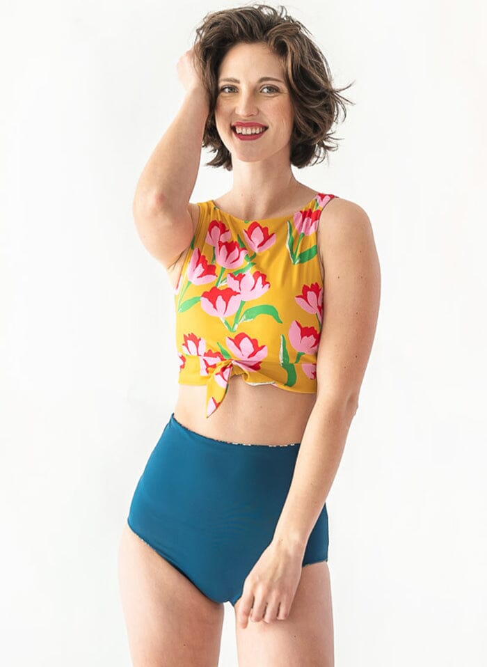 of a woman wearing a Blixen/Indigo reversible swim bottom indigo side and a yellow floral swim crop top