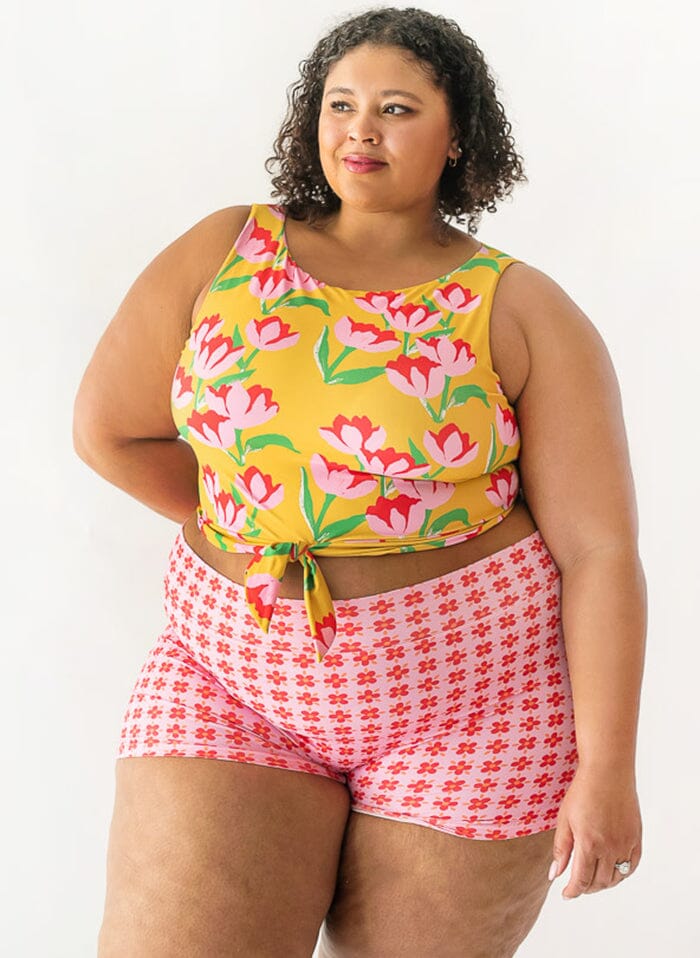 Photo of a woman wearing a Claus swim crop top and a floral swim short bottom