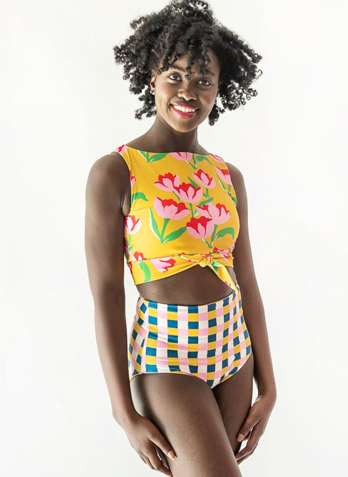 Photo of a woman wearing a Claus swim crop top and a multi color checkered swim bottom