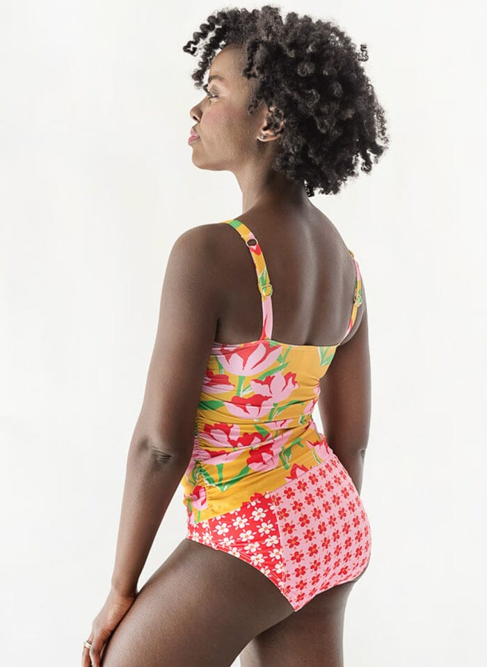 of a woman wearing a Claus square-neck swim top and a floral swim bottom side/back angle