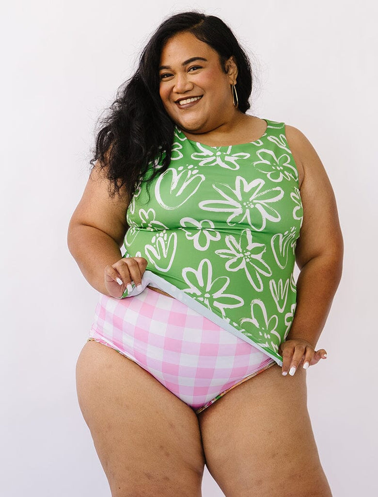 Photo of woman wearing a green and white floral boat neck tankini swim top with pink gingham swim bottoms