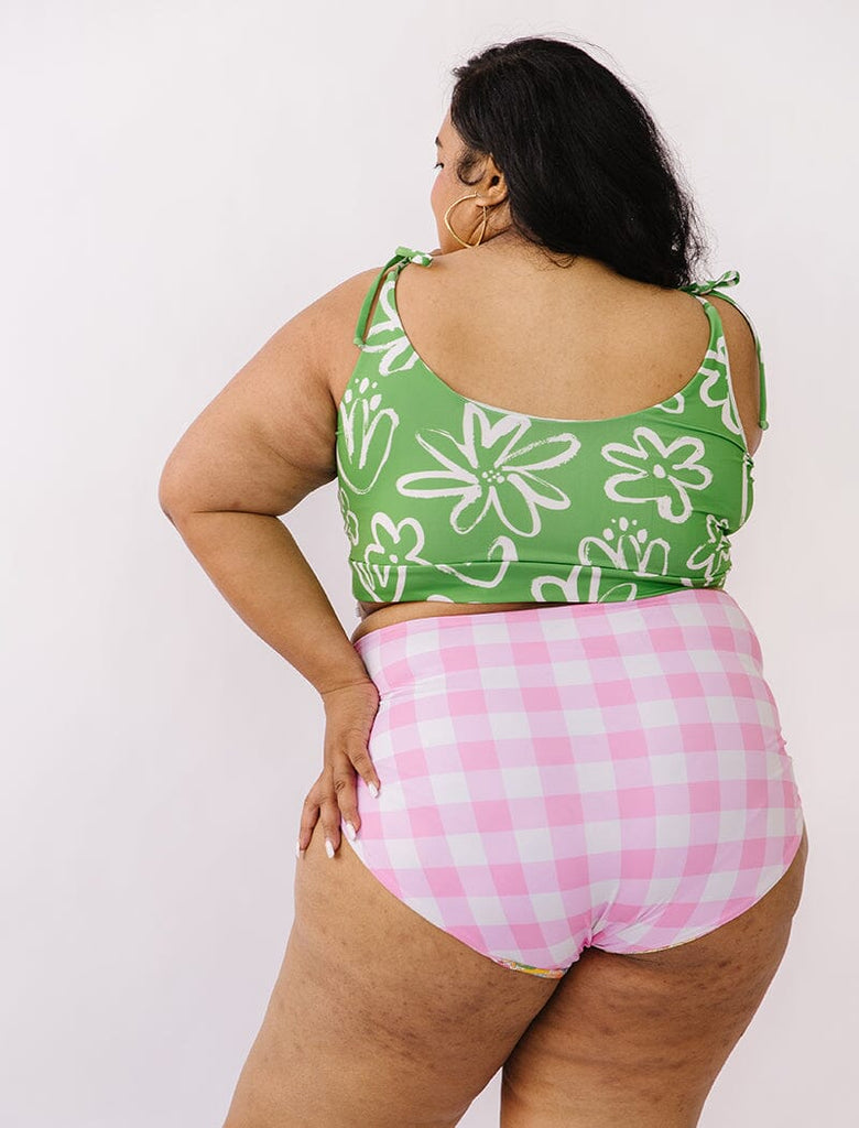 Photo of woman wearing green and white floral cropped swim top with pink gingham swim bottoms back angle