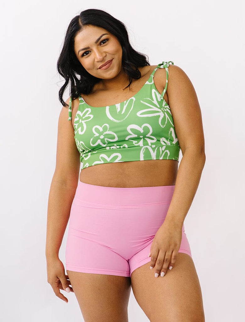 Photo of woman wearing green and white floral cropped swim top with pink swim shorts