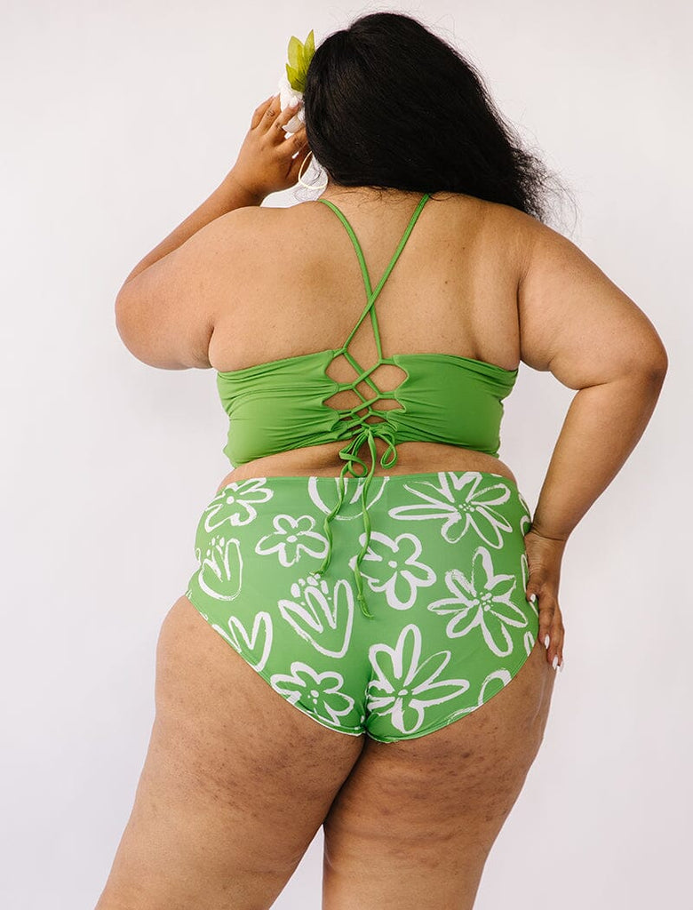 Photo of woman wearing green lace back cropped swim top with green and white floral swim bottoms back angle