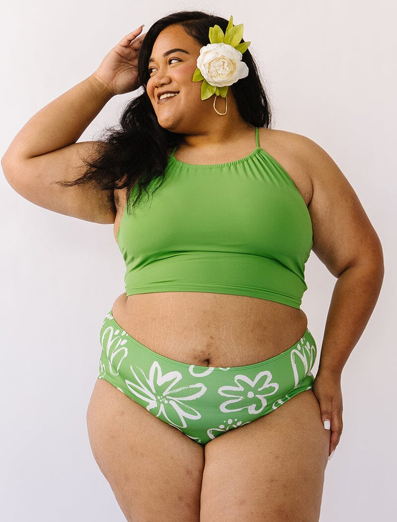 Photo of woman wearing green cropped swim top with green and white floral swim bottoms