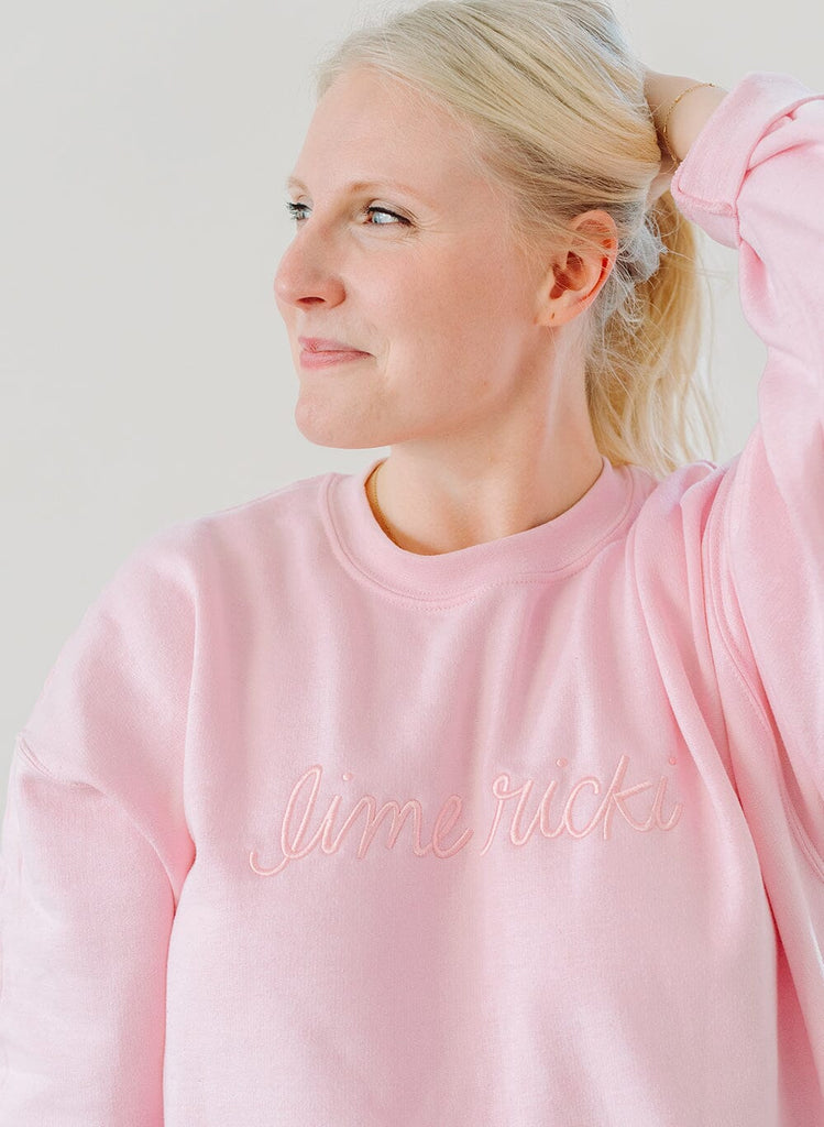 Photo of a woman wearing a pink crew neck sweatshirt