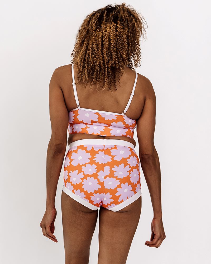 Photo of a woman wearing a Daphne floral swim bralette and a Daphne floral swim short bottom back angle