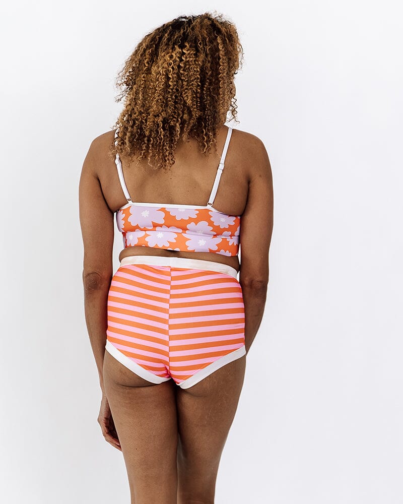 Photo of a woman wearing a Sherbet stripe retro swim short bottom and a Daphne floral swim bralette back angle