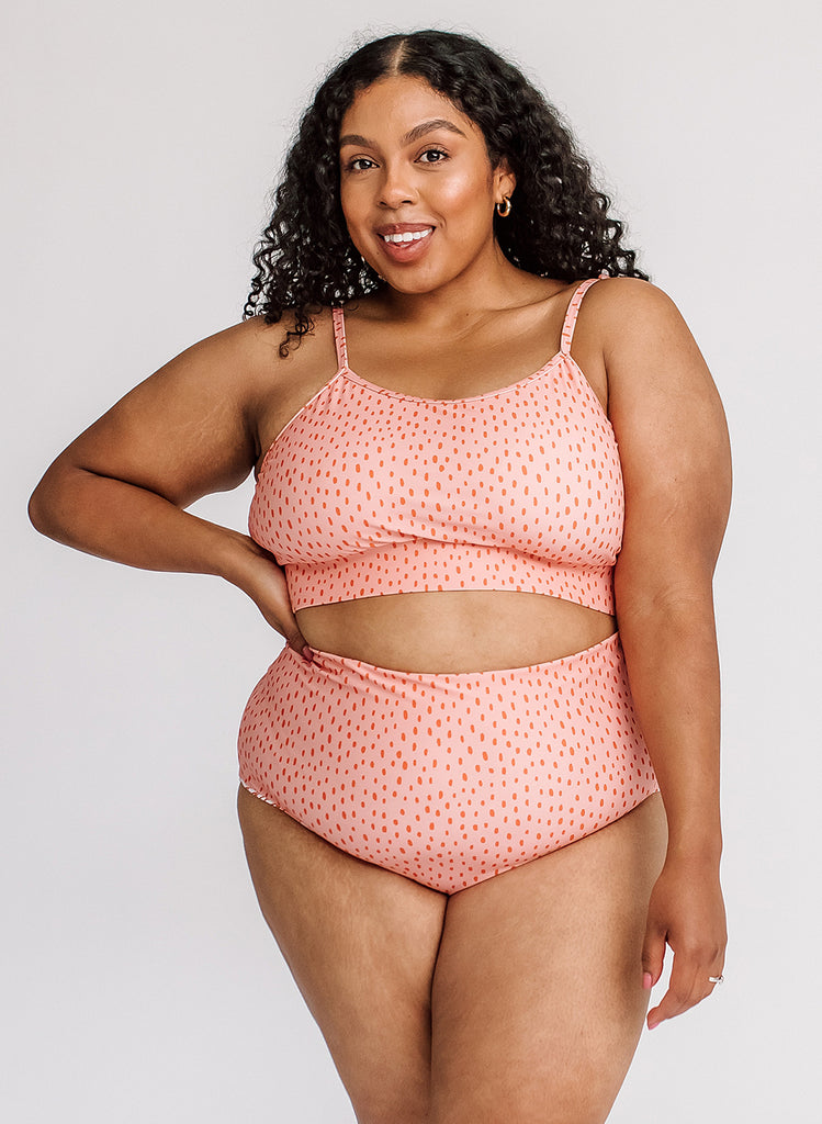 Photo of a woman with her hand on her hip wearing a pink polka dot cropped swim top with pink polka dot high waist swim bottoms