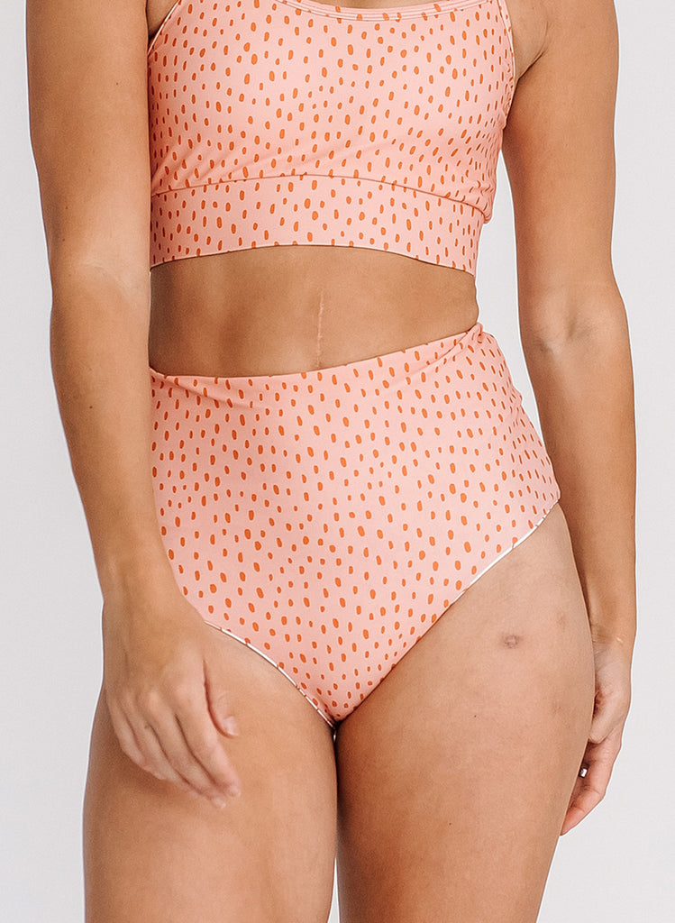 Photo of a woman wearing a pink dotted swim bralette and a pink dotted swim bottom