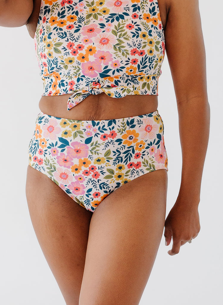 Close up photo of woman wearing multi colored floral cropped swim top with multi colored floral high waist swim bottoms
