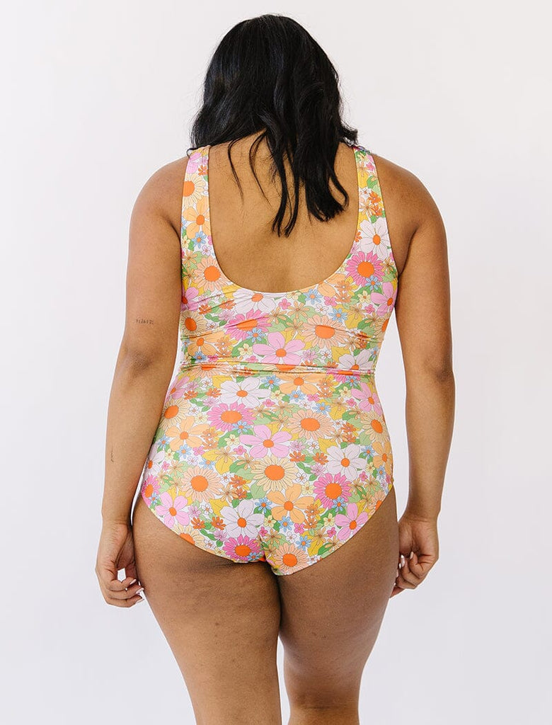 Photo of woman wearing multi colored floral knotted swim one piece back angle