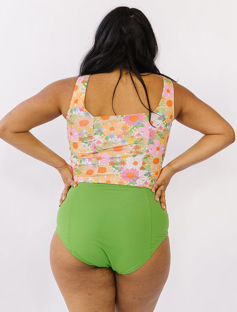 Photo of woman wearing multi colored cropped square neck swim top with green swim bottoms back angle