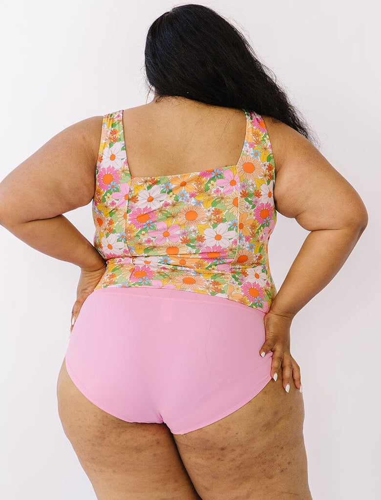 Photo of woman wearing multi colored floral square neck swim top with pink swim bottoms back angle
