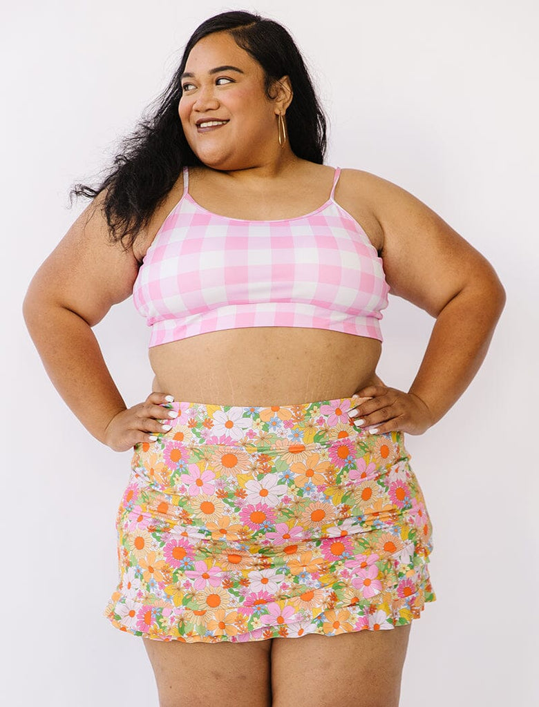 Photo of woman wearing pink gingham bralette swim top with multi colored floral swim skirt