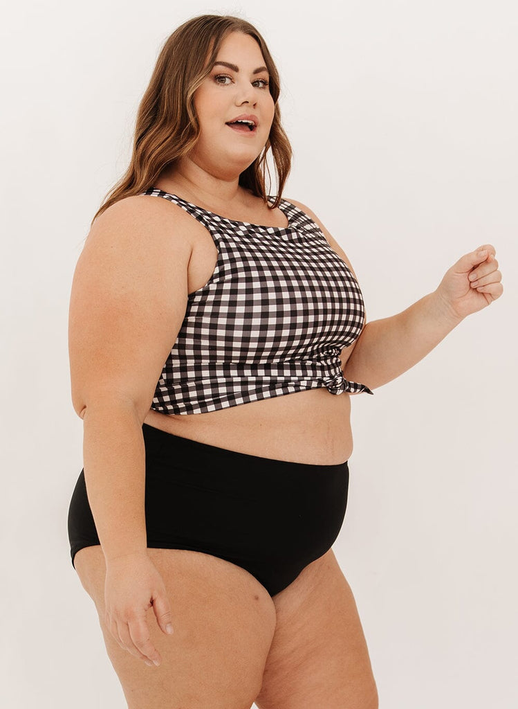 Photo of a woman wearing black ultra high-waist swim bottoms with a black gingham knotted crop swim top
