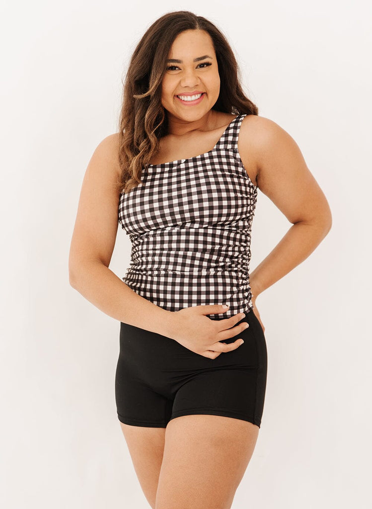 Photo of a woman wearing a black gingham square neck tankini swim top with black swim short bottoms