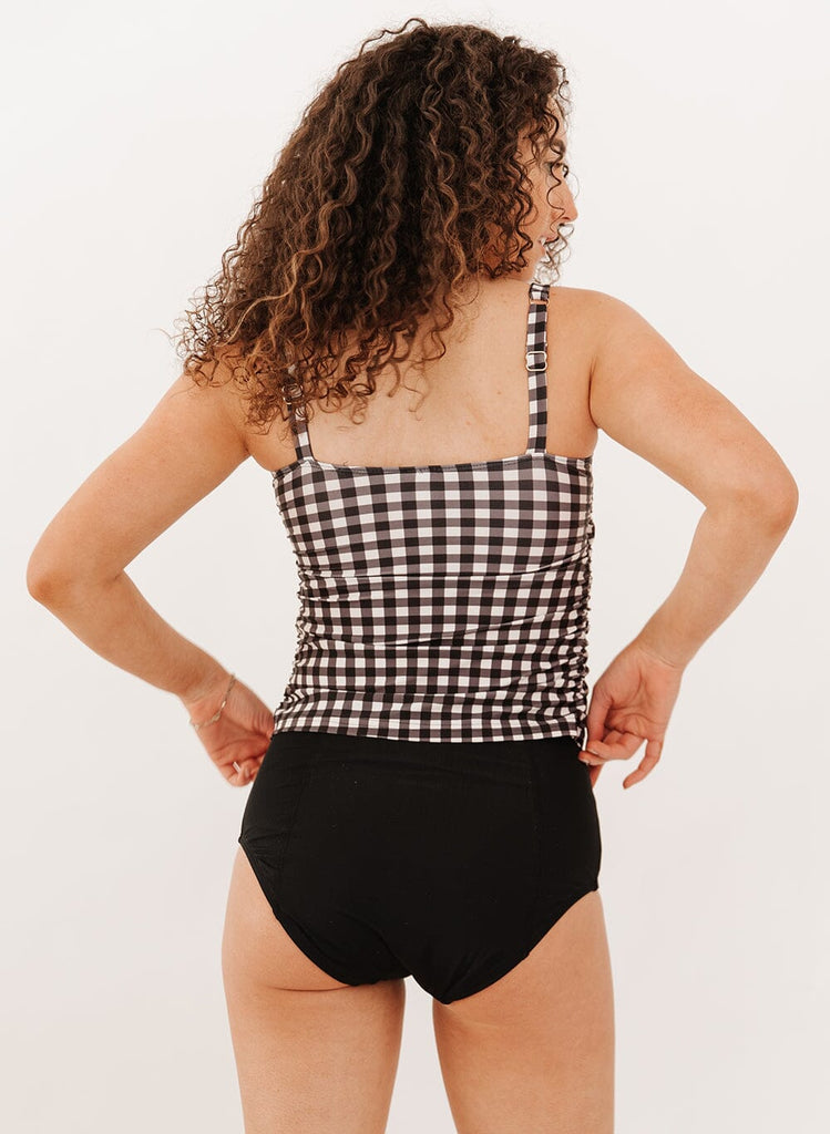 Photo of a woman wearing a black gingham square neck tankini swim top with black swim bottoms back angle