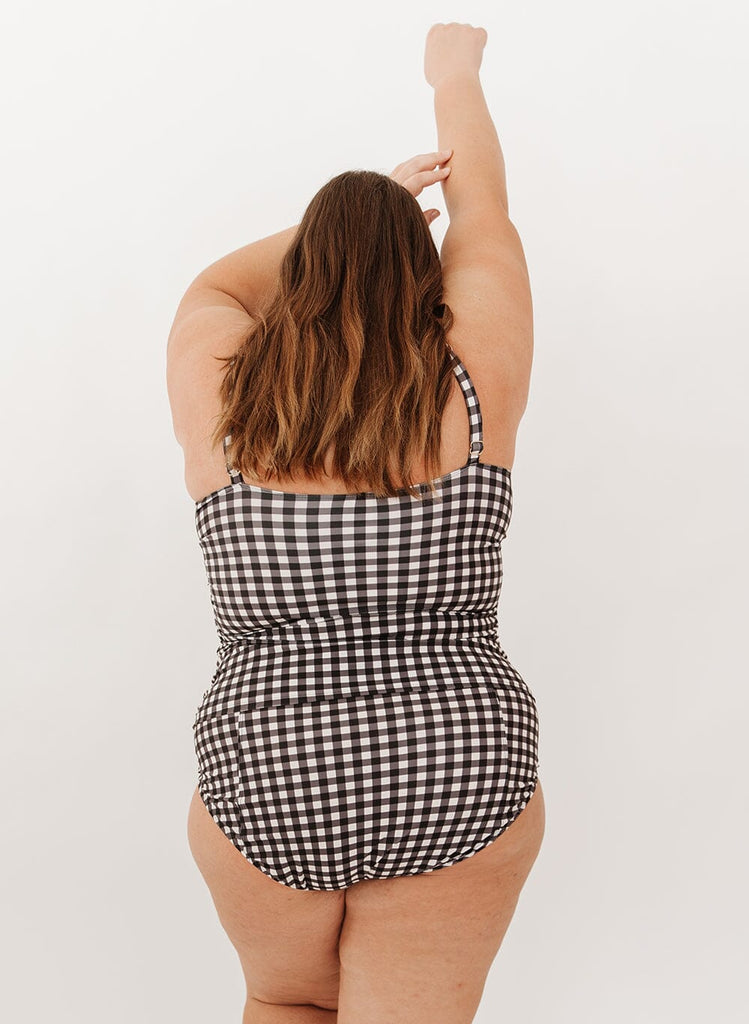 Photo of a woman wearing a black gingham square neck tankini swim top with black gingham high-waist swim bottoms back angle