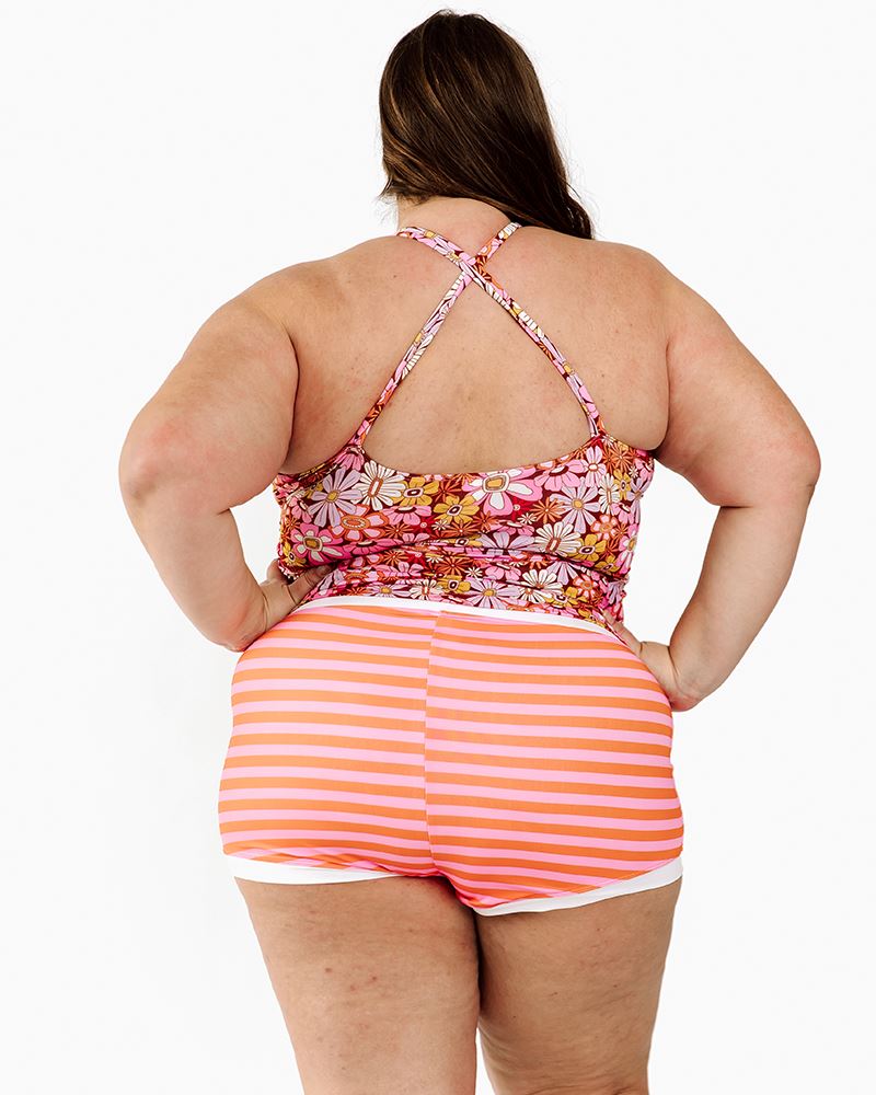 Photo of a woman wearing a Groovy Blooms floral double-cinch swim top and an orange and pink swim bottom back angle
