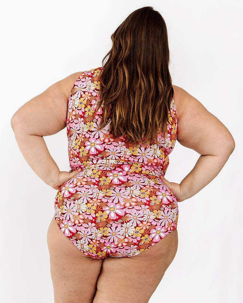 Photo of a woman wearing a Groovy Blooms floral knotted swim crop top and a Groovy Blooms floral swim bottom back angle