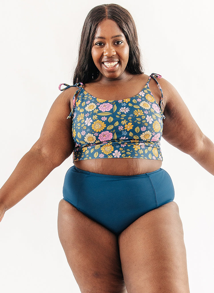 Photo of woman wearing multi color floral cropped swim top with blue swim bottoms