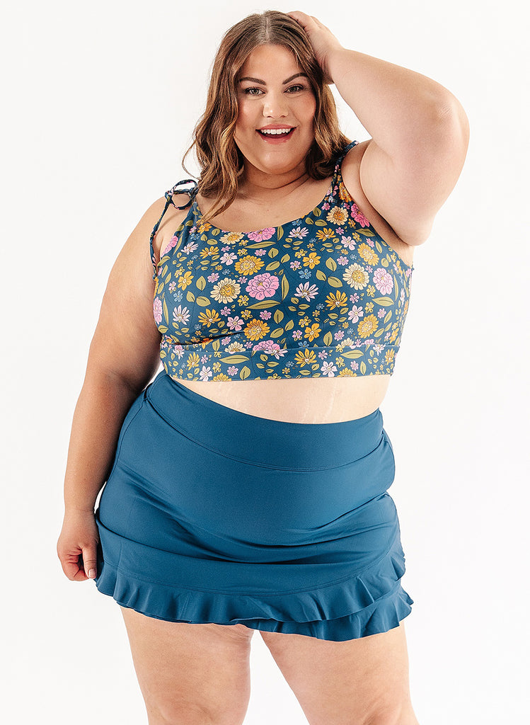 Photo of woman wearing multi color floral cropped swim top with blue swim skirt