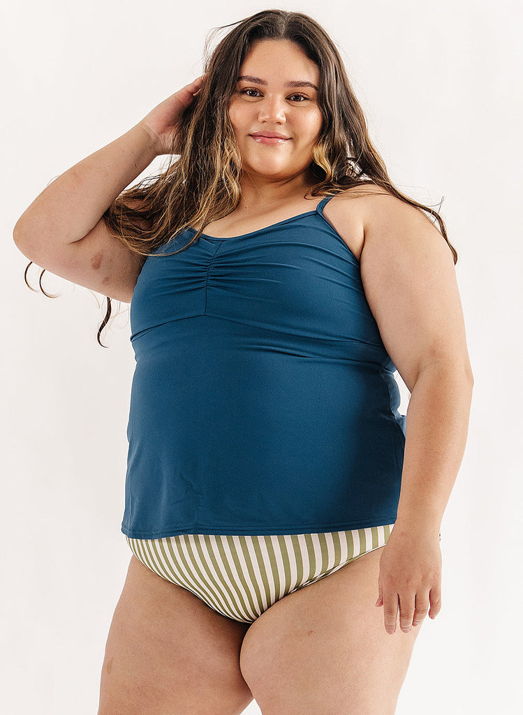 Photo of woman wearing blue swim tankini with green and white stripe swim bottoms