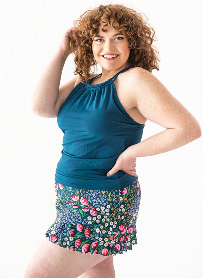 Photo of a woman wearing a Blixen swim skirt bottom and an indigo double-cinch swim top side angle