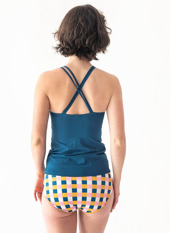 Photo of a woman wearing an Indigo double-cinch swim top and a multi color checkered swim bottom back angle