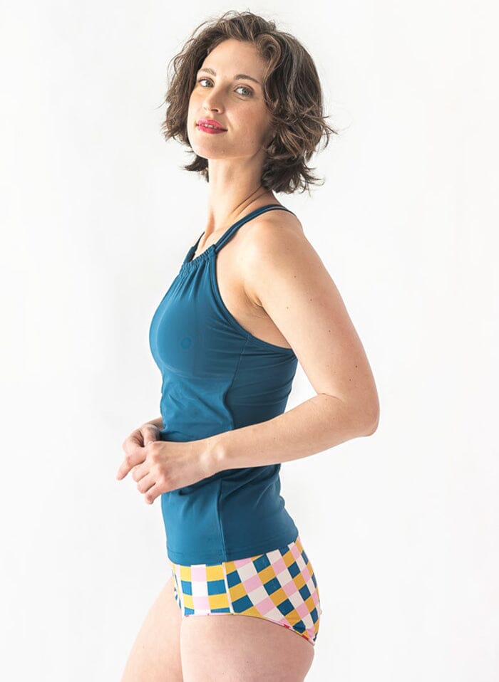 Photo of a woman wearing an Indigo double-cinch swim top and a multi color checkered swim bottom side angle