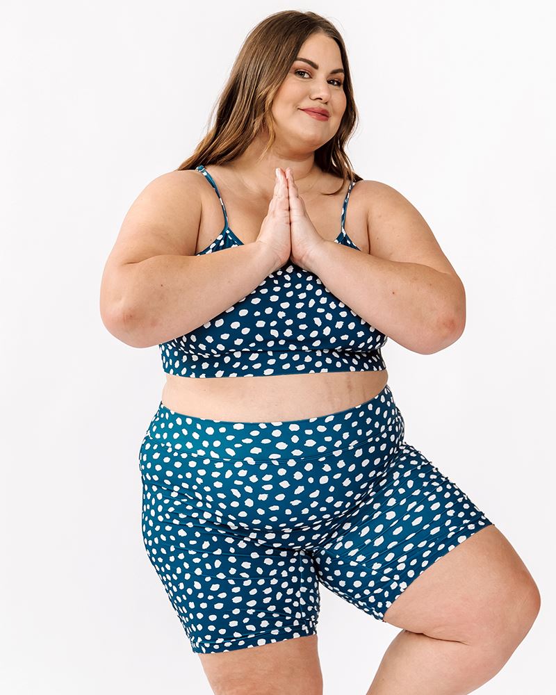 Photo of a woman wearing an Indigo dot Swim bike short and an Indigo dot swim bralette in a yoga pose