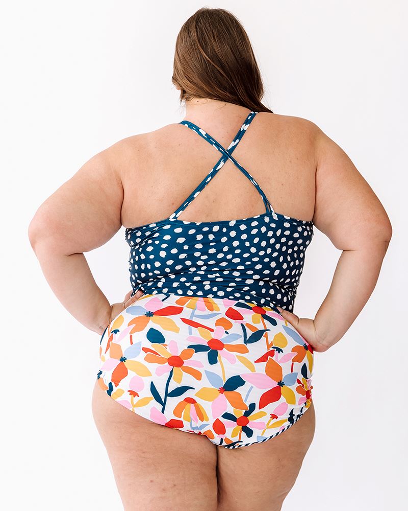 Photo of a woman wearing an Indigo dot double-cinch swim top and a multi color floral swim bottom back angle