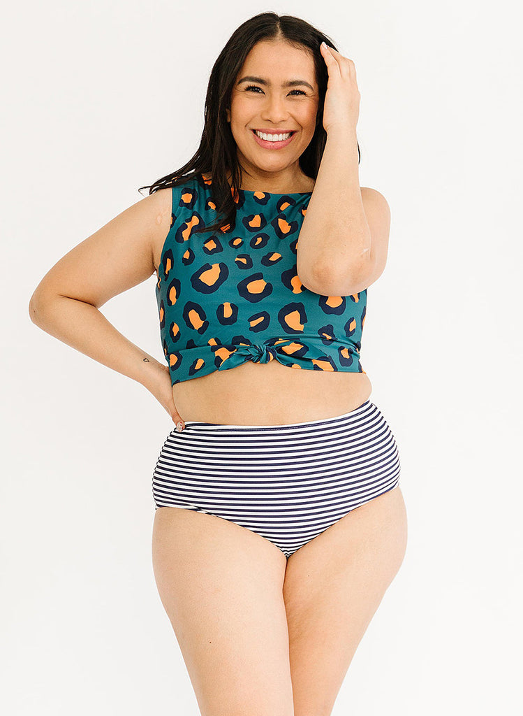 Photo of woman wearing blue leopard print cropped swim top with blue and white striped high waist swim bottoms