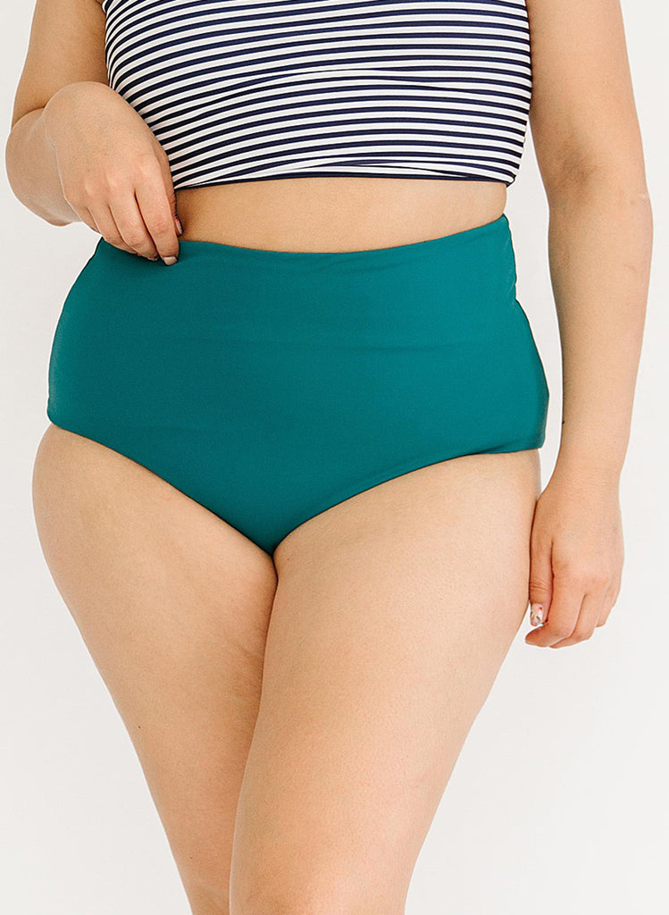 Close up photo of woman wearing a blue and white striped cropped swim top with blue high waisted swim bottoms