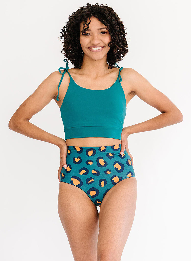 Photo of woman wearing a blue cropped swim top with blue leopard print high waist bottoms