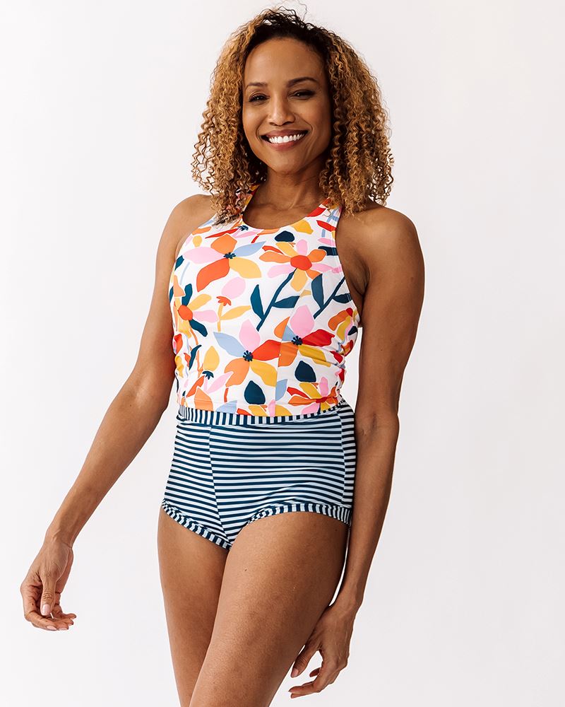 Photo of a woman wearing an Indigo retro swim short bottom and a multi color floral swim crop top