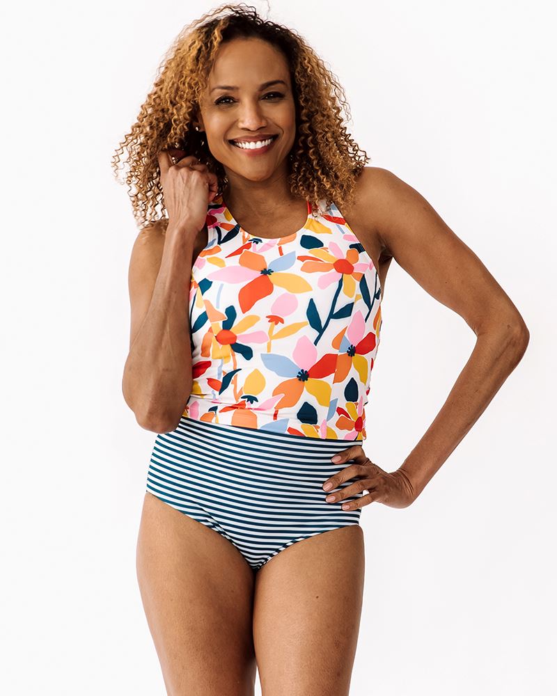 Photo of a woman wearing a June floral/ Indigo stripe reversible swim bottom stripe side and a June floral swim crop top