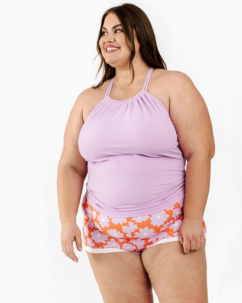 Photo of a woman wearing a Lilac double-cinch swim top and a Daphne floral swim short bottom