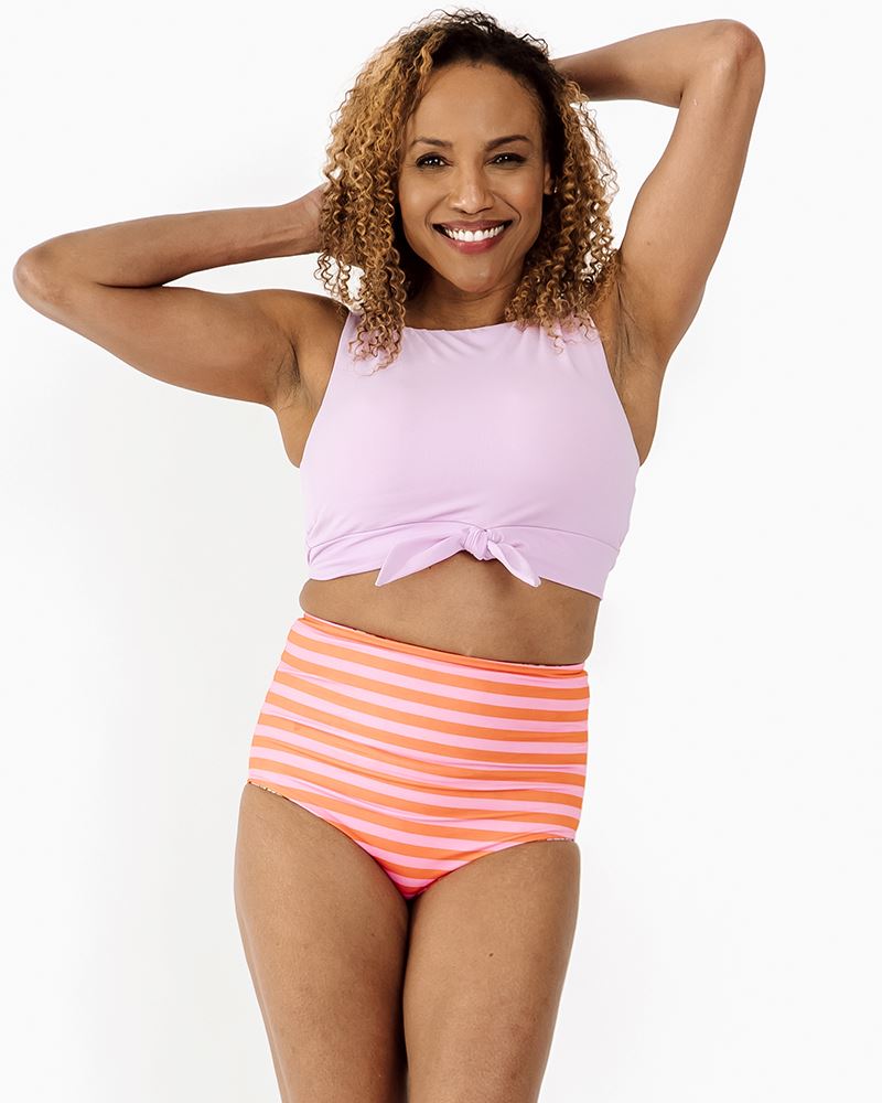 Photo of a woman wearing a Lilac knotted swim crop top and a sherbet stripe swim bottom