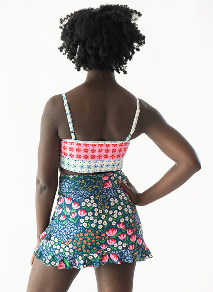 Photo of a woman wearing a Blixen swim skirt bottom and a floral swim bralette back angle
