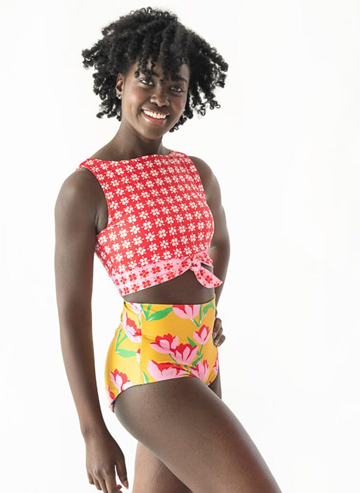 Photo of a woman wearing a Claus/Tage reversible swim bottom Claus side and a floral swim crop top side angle